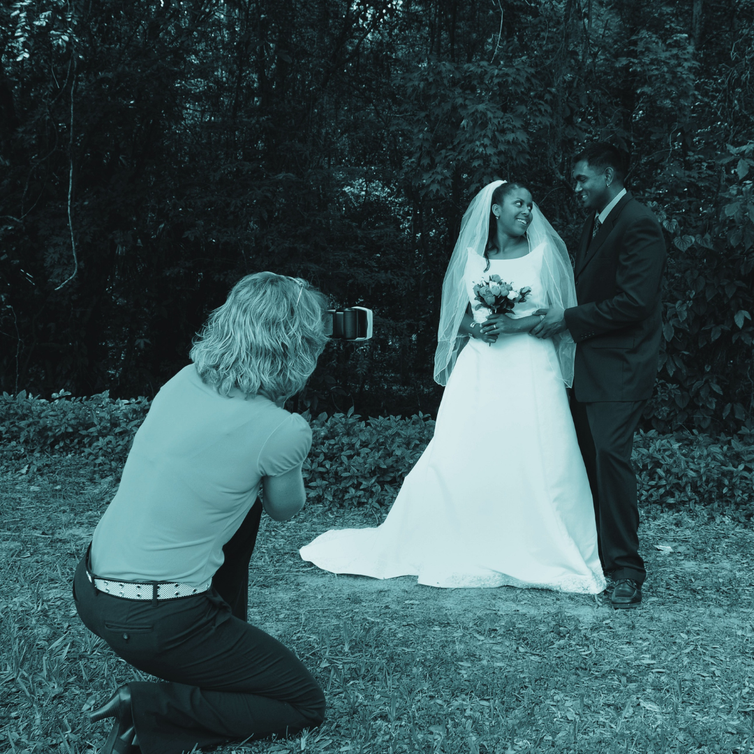 blue filtered wedding photographer taking photo of bride and groom next to trees